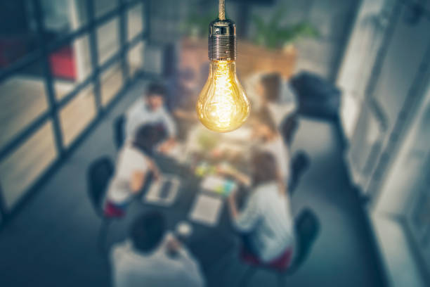 Light bulb shining above a group of researchers sitting at a table